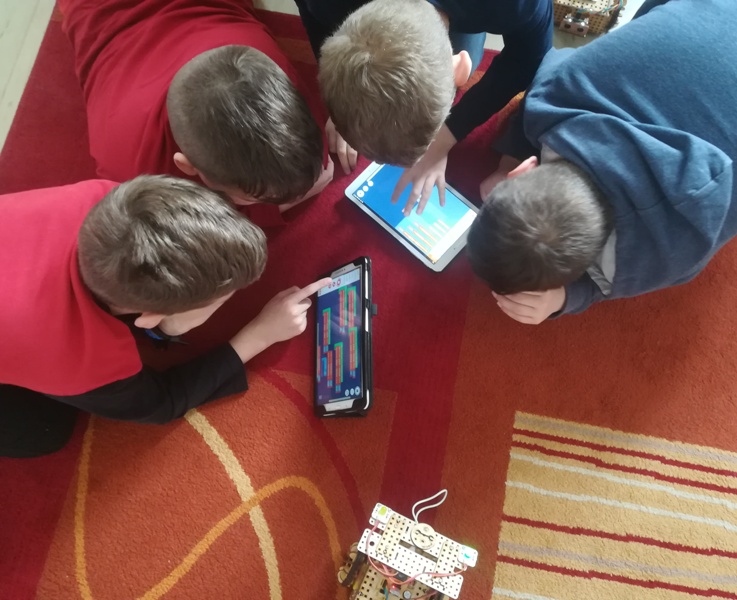 Czterech chłopców programuje robota Lofi.