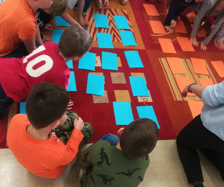 Dzieci biorą udział w zabawie z kartkami koloru pomarańczowego i zielonego.